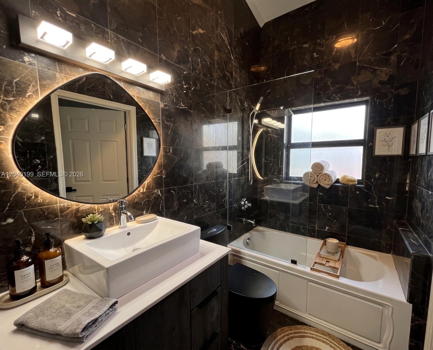 A bathroom features dark marble tile walls, a vessel sink, and a glass-enclosed bathtub — 4605 N Miami Ave, Miami FL 33127, MIAMI, FL