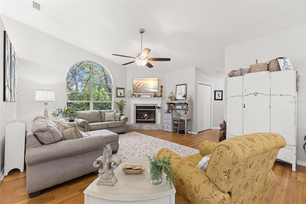 A living room features a fireplace, a large arched window, and hardwood flooring — 3734 THORNBUSH LANE, NEW PORT RICHEY, FL
