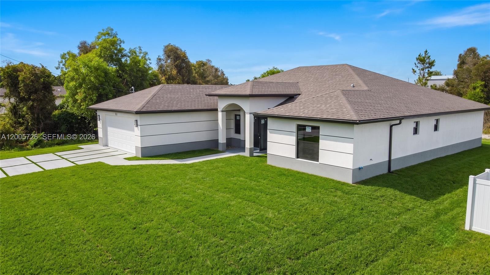 A modern single-story house with a white exterior, gray trim, and a hip roof — 813 Bell Blvd S, Lehigh Acres FL 33974, LEHIGH ACRES, FL