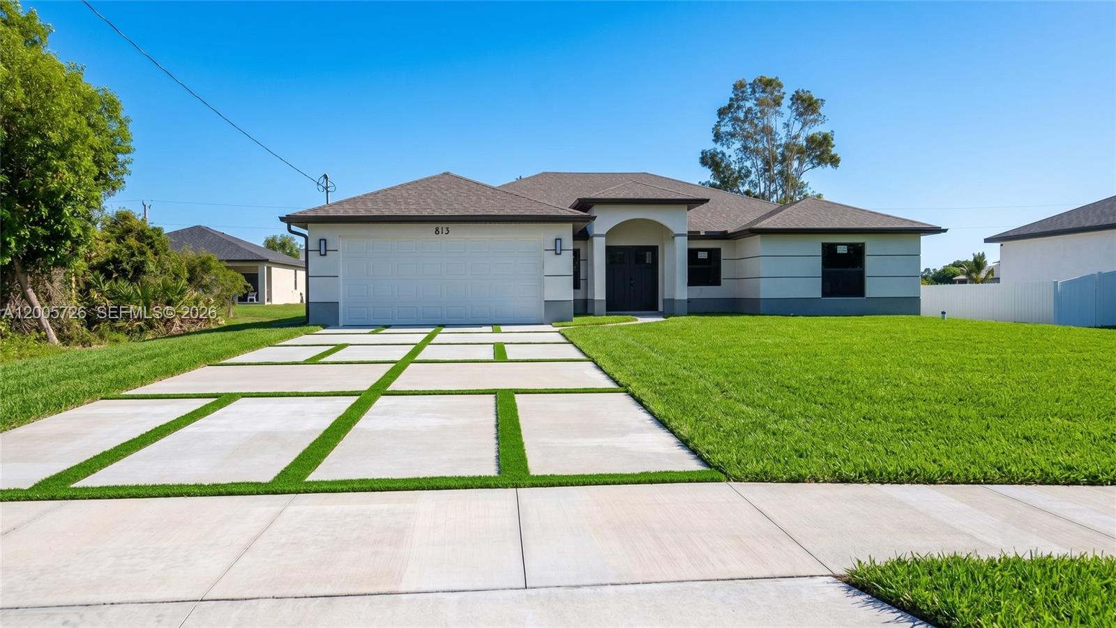 A single-story house with a white garage, a grid-pattern driveway, and a green lawn — 813 Bell Blvd S, Lehigh Acres FL 33974, LEHIGH ACRES, FL