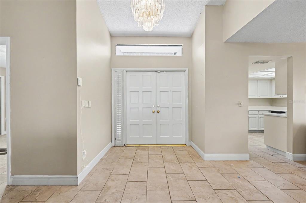 An entryway features double front doors, a crystal chandelier, and light-colored tile flooring — 11502 ROBLES DEL RIO PLACE, TEMPLE TERRACE, FL