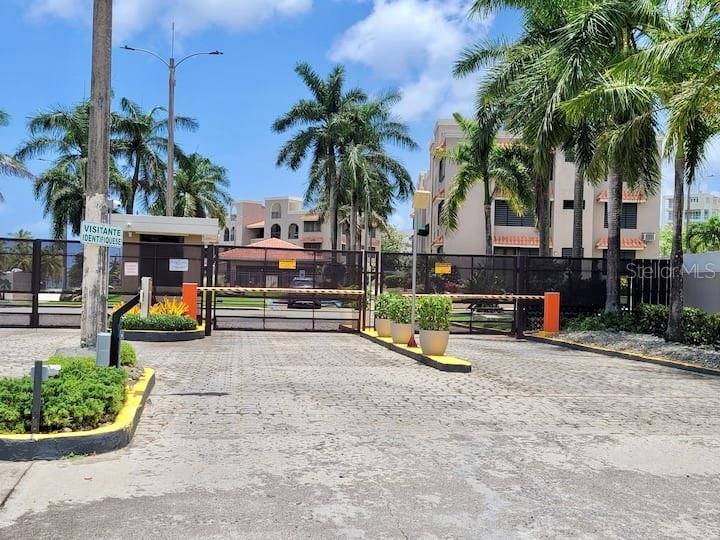 A gated entrance leads to a multi-story residential building surrounded by palm trees — CARR 3 KM 66.7 CALA DE HUCARES UNIT C210, NAGUABO, PR