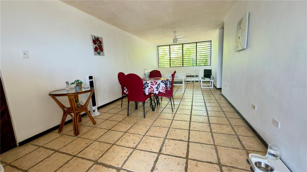 A dining room with tiled floors, a round table with red chairs, and large windows — CARR 3 KM 66.7 CALA DE HUCARES UNIT C210, NAGUABO, PR
