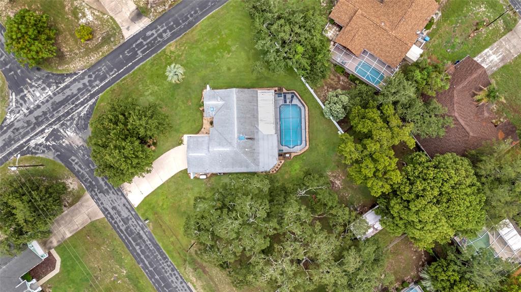 An aerial view shows a house with a pool and driveway on a grassy lot — 5325 ABAGAIL DRIVE, SPRING HILL, FL
