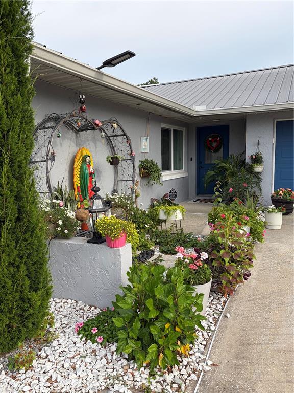 A house exterior features a statue of the Virgin Mary, potted plants, and white gravel — 4119 SUNNY LAND DRIVE, LAKELAND, FL