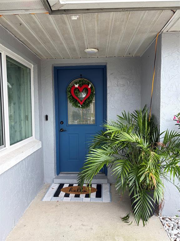 A blue front door with a heart wreath sits under a covered porch with a plant — 4119 SUNNY LAND DRIVE, LAKELAND, FL