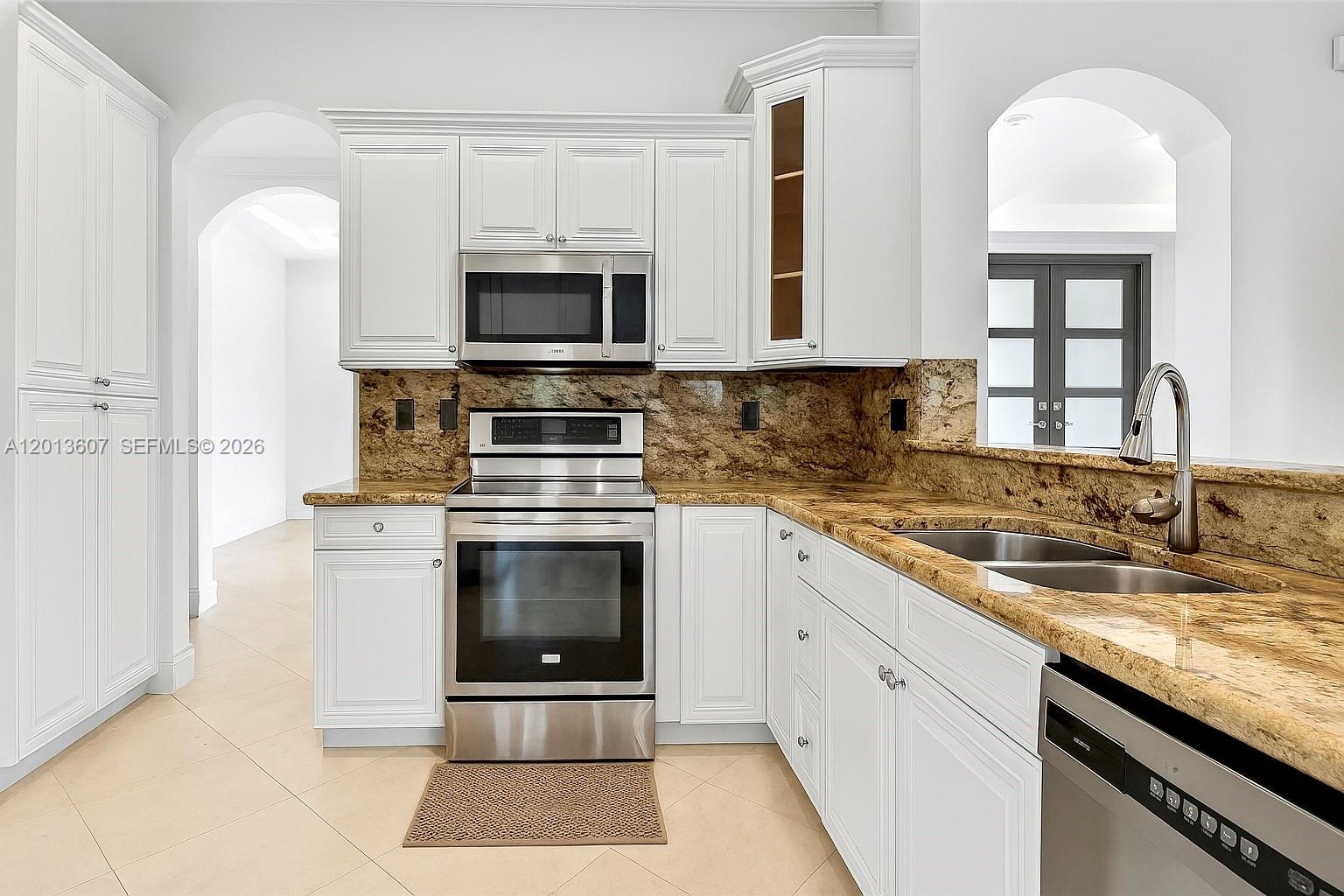 A kitchen features white cabinets, granite countertops, stainless steel appliances, and tile flooring — 16763 NW 77th Path, Miami Lakes FL 33016, MIAMI LAKES, FL