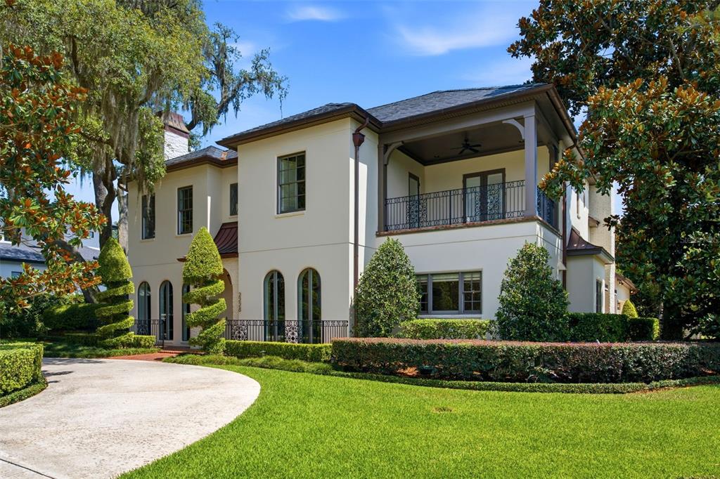 A two-story stucco house with a covered balcony, arched windows, and a circular driveway — 2228 AZALEA PLACE, WINTER PARK, FL