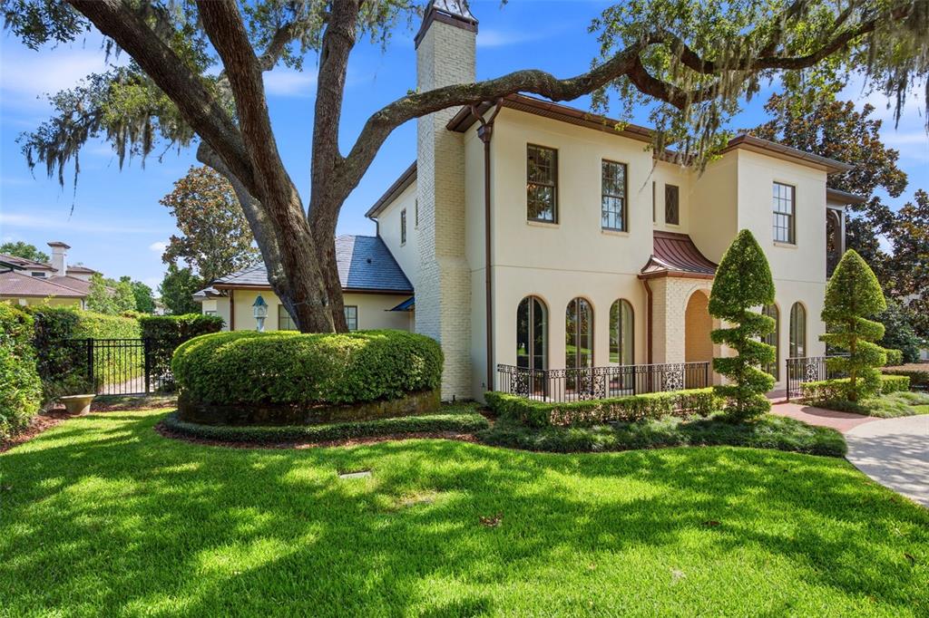 A two-story stucco house features a prominent brick chimney, arched windows, and a large oak tree — 2228 AZALEA PLACE, WINTER PARK, FL