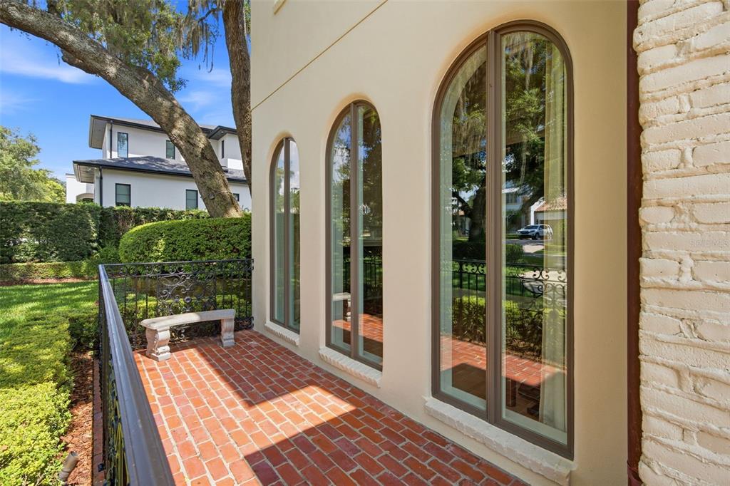 A brick patio features a stone bench and arched windows along a stucco exterior wall — 2228 AZALEA PLACE, WINTER PARK, FL