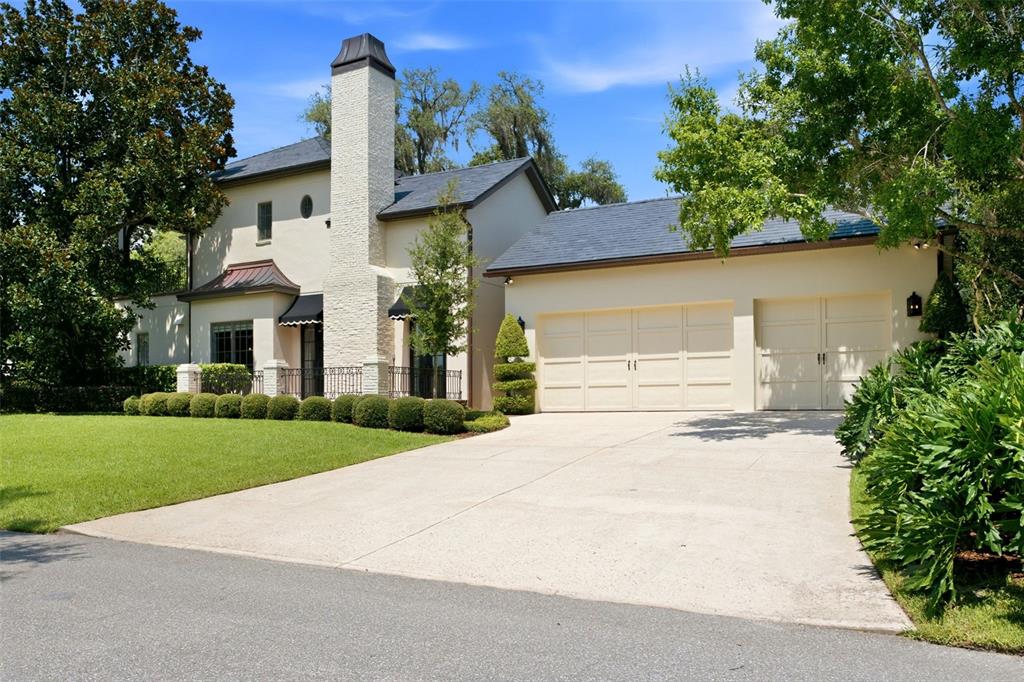A two-story stucco house with a stone chimney, slate roof, and attached two-car garage — 2228 AZALEA PLACE, WINTER PARK, FL