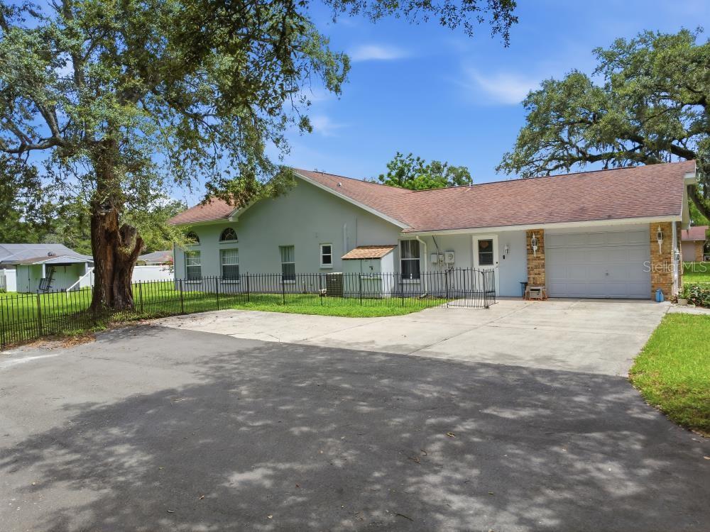 A single-story house with a light green exterior, a two-car garage, and a fenced yard — 483 LINCOLN AVENUE, MASARYKTOWN, FL