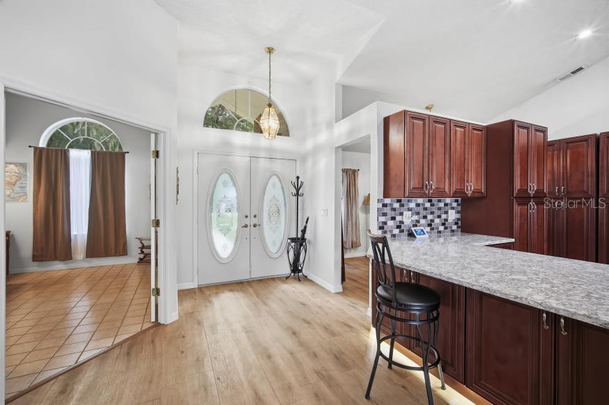 An entryway with a double front door leads to a kitchen featuring dark wood cabinets — 483 LINCOLN AVENUE, MASARYKTOWN, FL