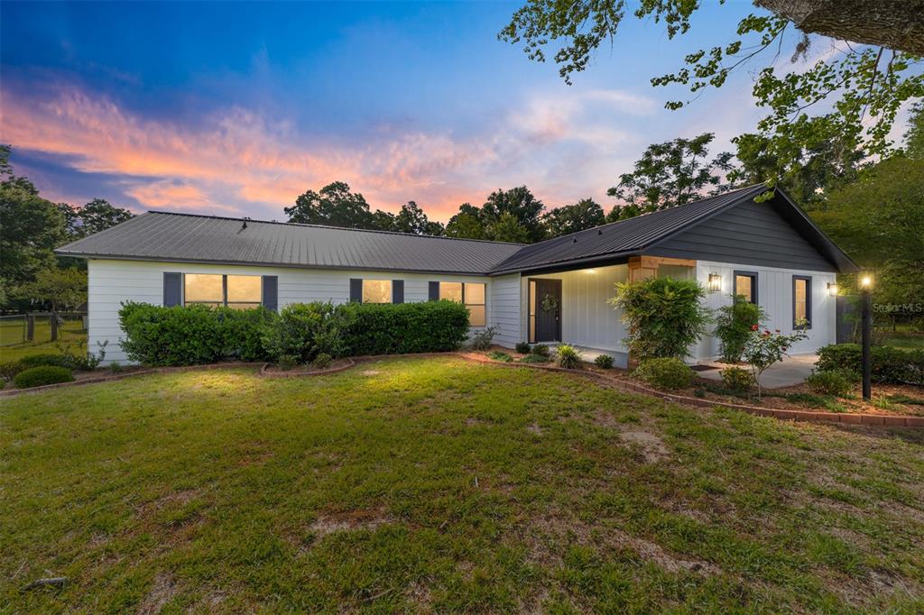 A single-story house with white siding, a dark metal roof, and a front porch — 10575 SW 27TH AVENUE, OCALA, FL