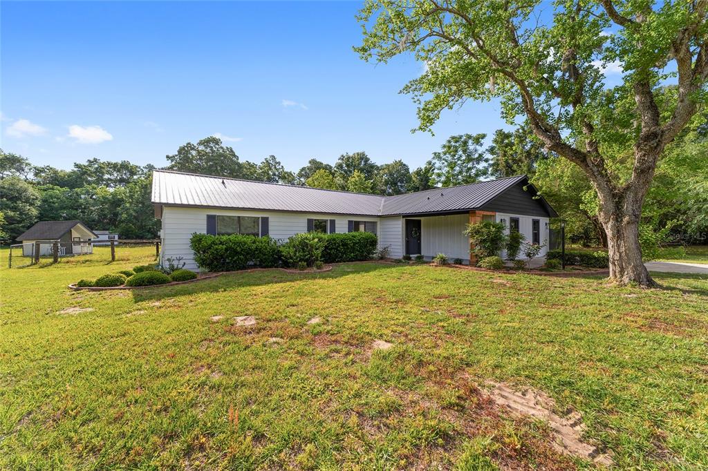A detached three-car garage with wood-look doors sits on a concrete pad near trees — 10575 SW 27TH AVENUE, OCALA, FL