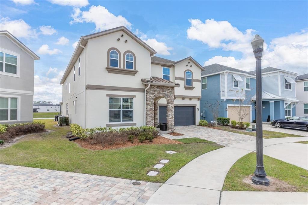 A two-story house with a stone-accented entryway, a two-car garage, and a paved driveway — 8904 CAROLINE BAY COURT, KISSIMMEE, FL