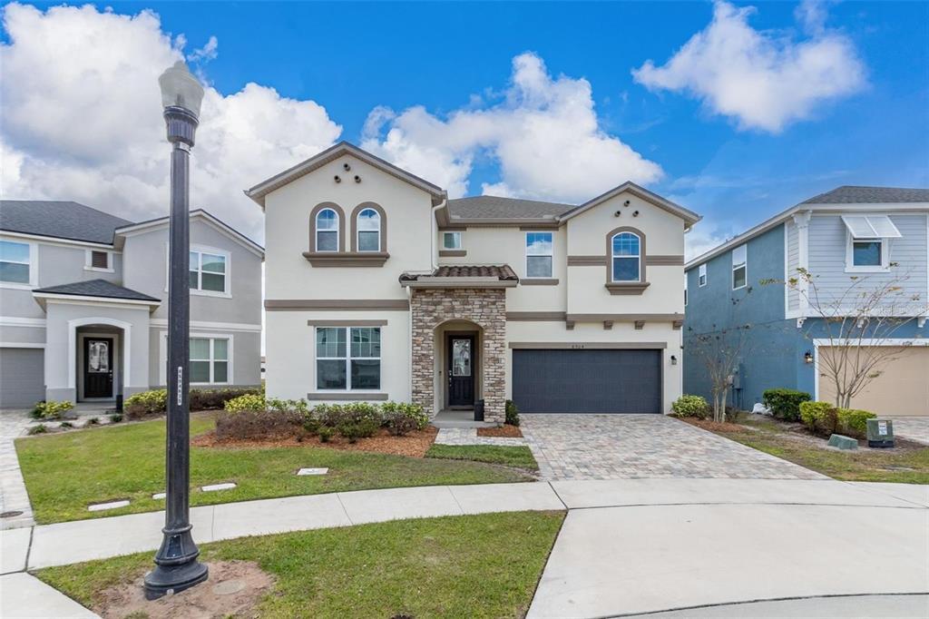 A two-story suburban house with a stone-accented entryway, dark garage door, and arched windows — 8904 CAROLINE BAY COURT, KISSIMMEE, FL
