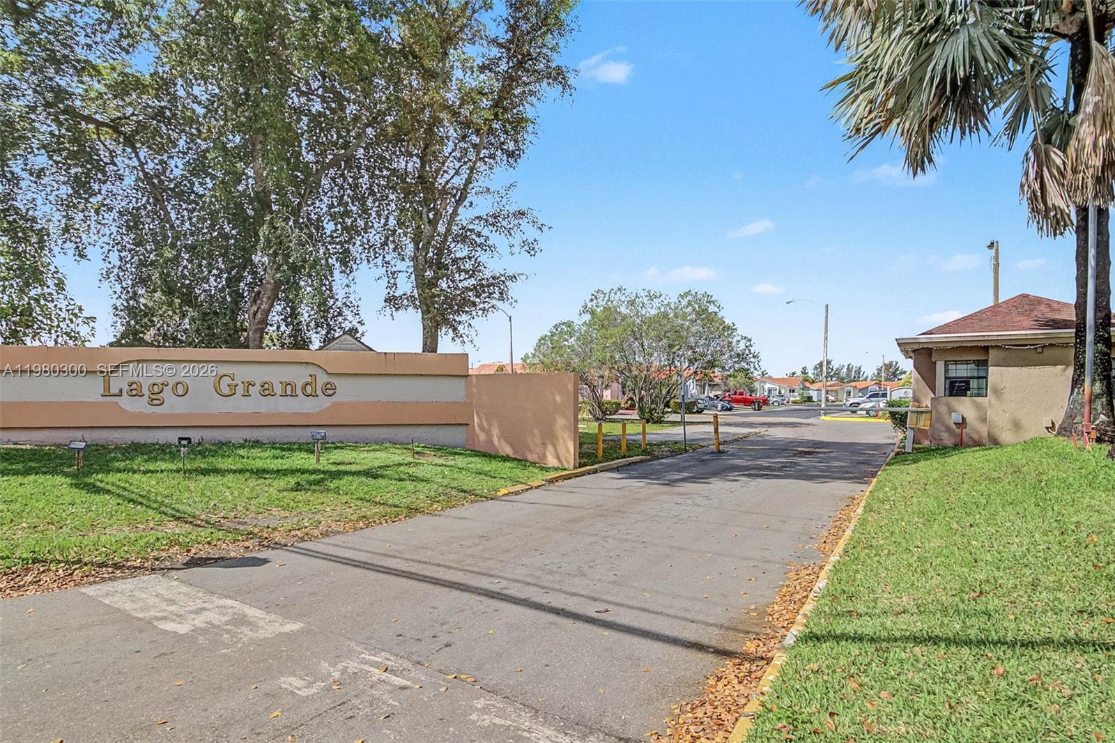 The entrance to the Lago Grande community features a tan wall sign and a guardhouse — 6525 W 26th Dr # 37, Hialeah FL 33016, HIALEAH, FL