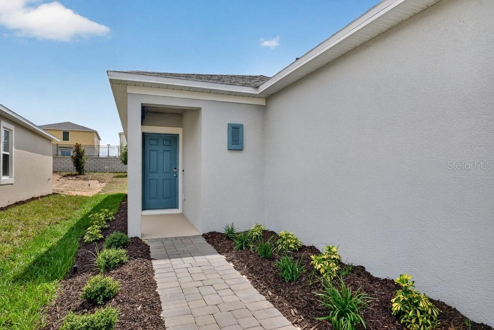 A paved walkway leads to the blue front door of a light-colored stucco house — 379 CORNERSTONE DRIVE, GROVELAND, FL