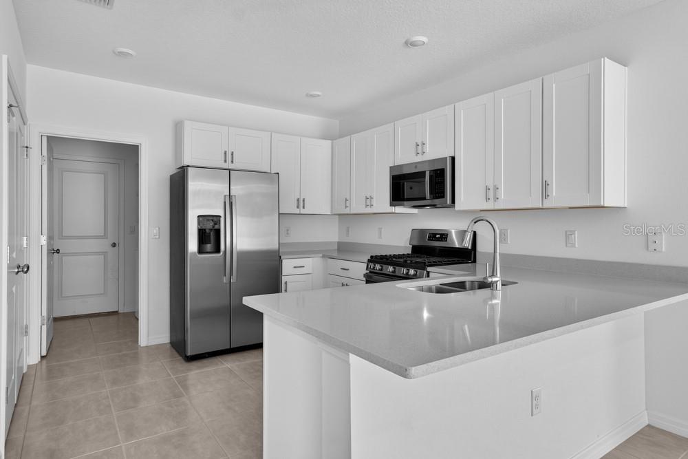 A kitchen with white cabinets, stainless steel appliances, and a gray countertop island — 379 CORNERSTONE DRIVE, GROVELAND, FL