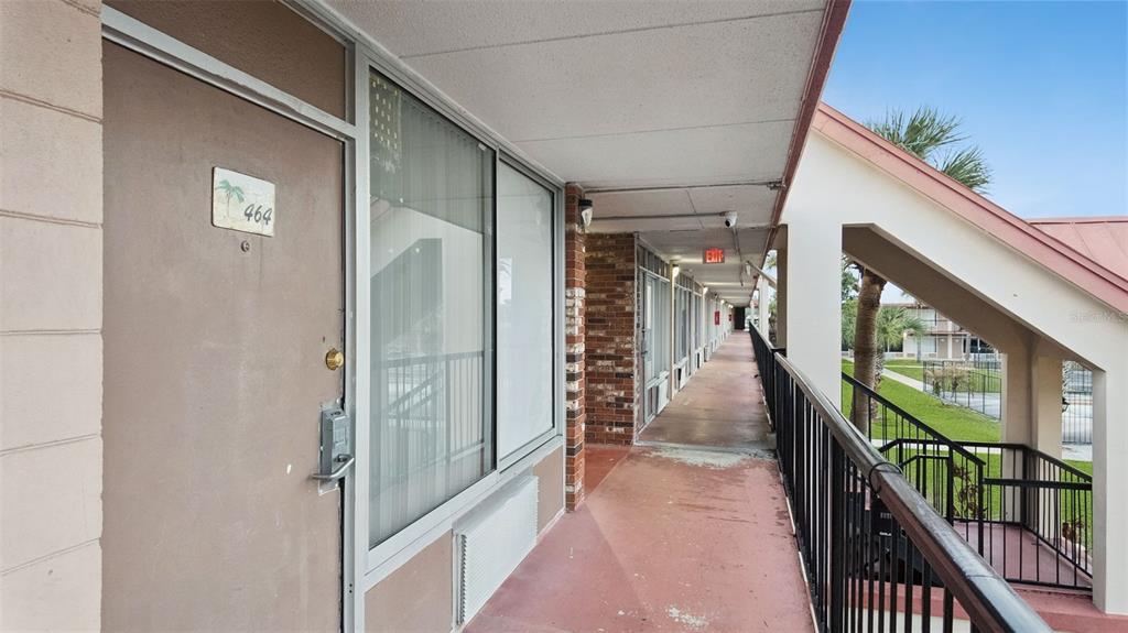 An exterior walkway leads past a door numbered 464 toward an exit sign — 43420 HIGHWAY 27 UNIT 464, DAVENPORT, FL