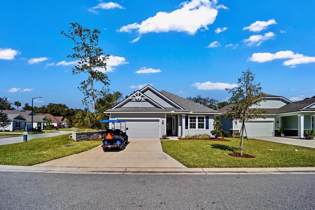 A single-story gray house with a two-car garage and a golf cart in the driveway — 50 MOANA COURT S, PALM COAST, FL