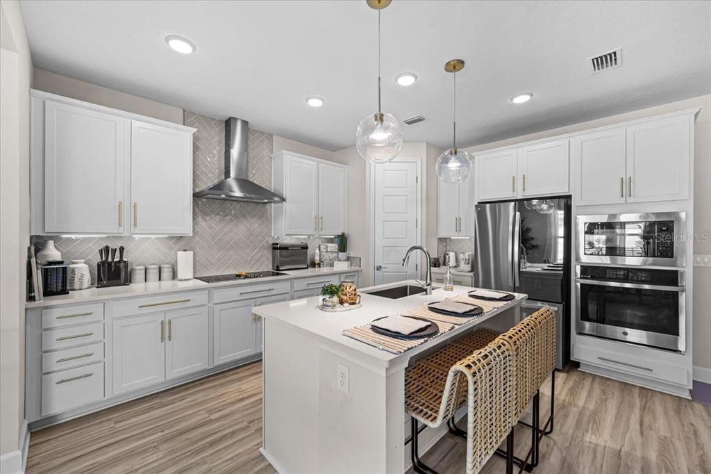 A modern kitchen features white cabinetry, a center island with seating, and stainless steel appliances — 50 MOANA COURT S, PALM COAST, FL