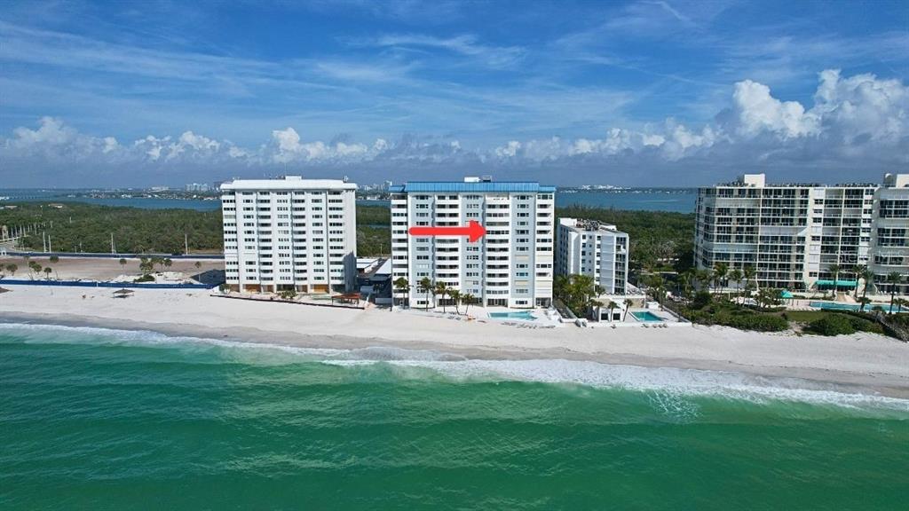 An aerial view of three beachfront high-rise condominium buildings along a sandy coastline — 1750 BENJAMIN FRANKLIN DRIVE UNIT 9B, SARASOTA, FL