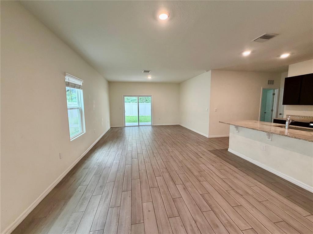 An open-concept living area features light wood-look tile flooring, white walls, and a kitchen island — 4802 SW 51ST WAY, GAINESVILLE, FL