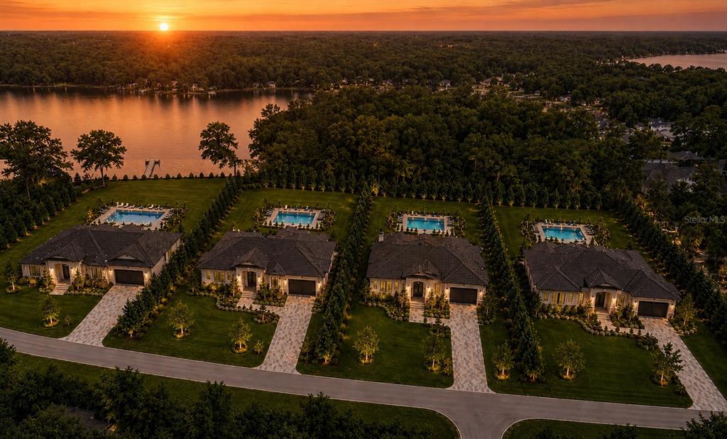 An aerial view shows four luxury houses with swimming pools along a lake at sunset — 1444 CHESAPEAKE DRIVE, ODESSA, FL