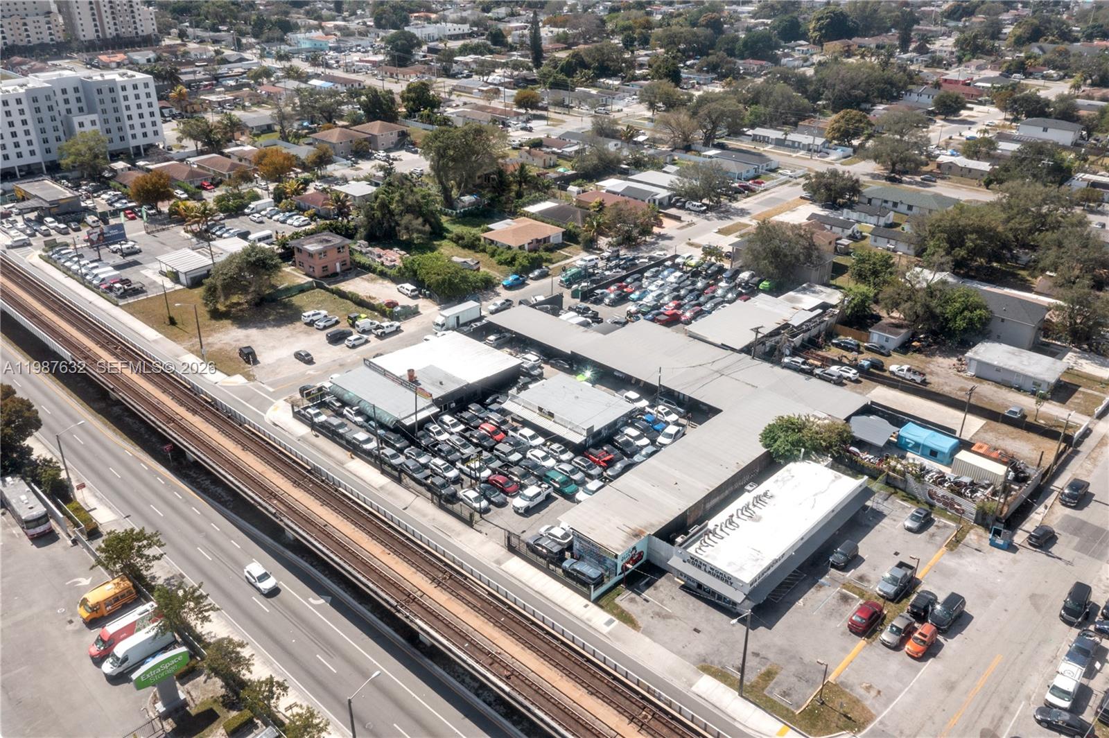 An aerial view shows a commercial building complex with a large parking lot near train tracks — 5700 NW 27th Ave, Miami FL 33142, MIAMI, FL