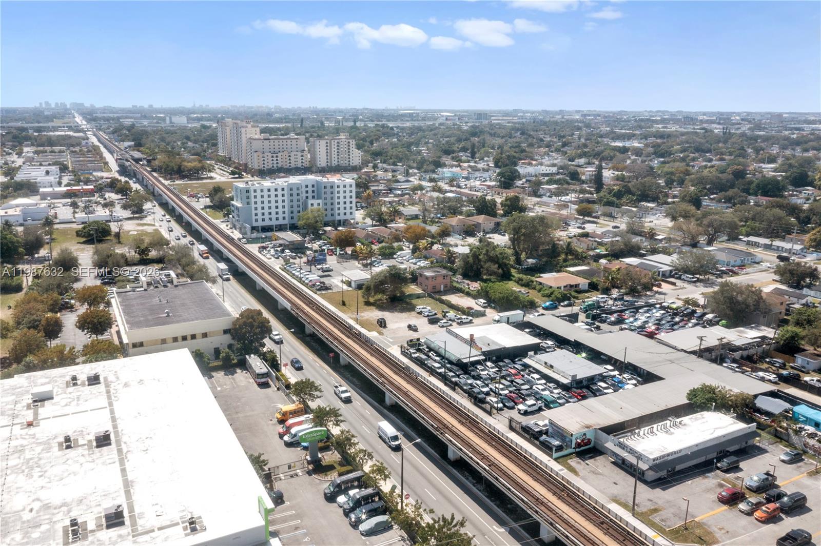 An elevated train track runs through a suburban area with parking lots and buildings — 5700 NW 27th Ave, Miami FL 33142, MIAMI, FL
