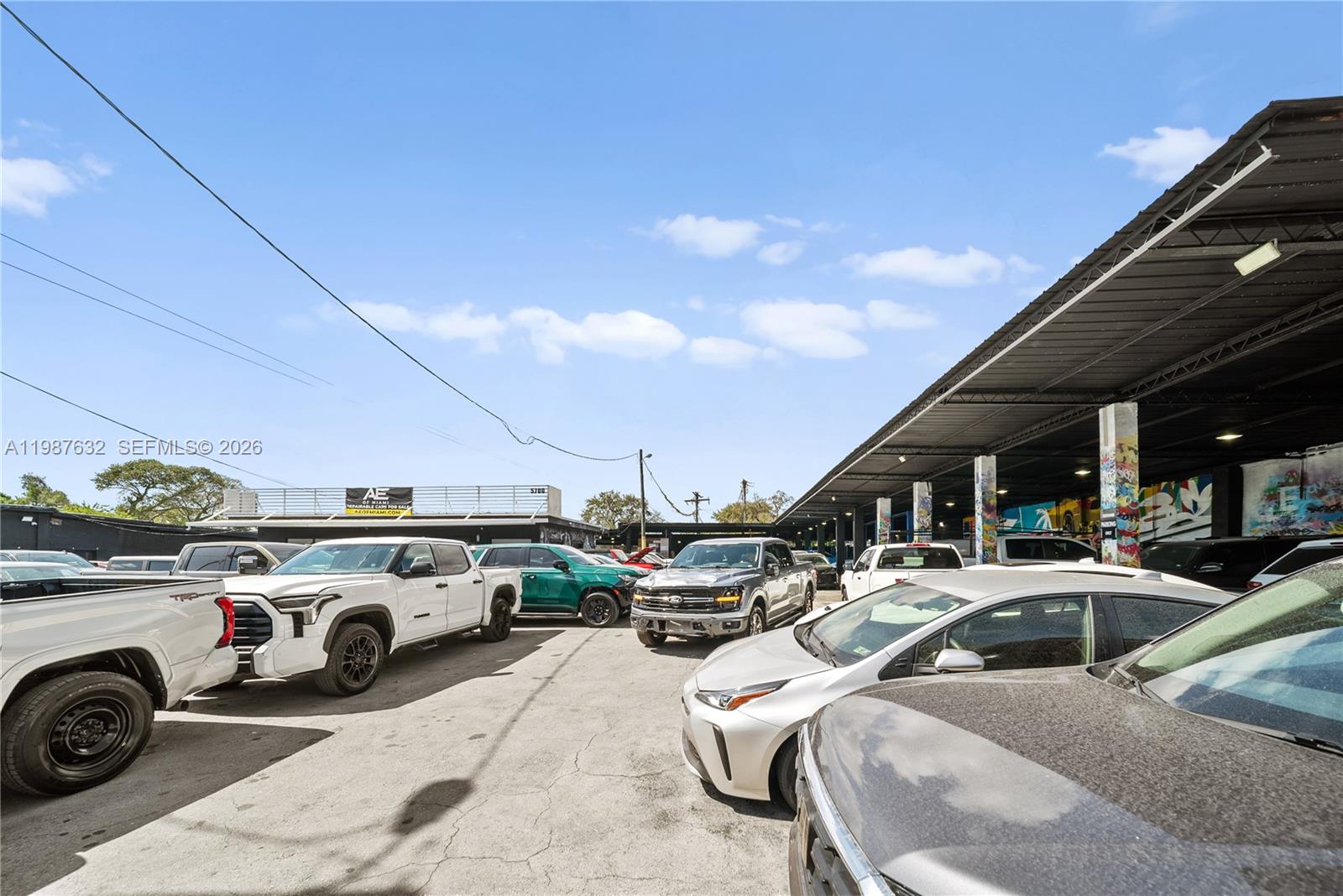 An outdoor car lot features several parked vehicles under a large metal canopy structure — 5700 NW 27th Ave, Miami FL 33142, MIAMI, FL