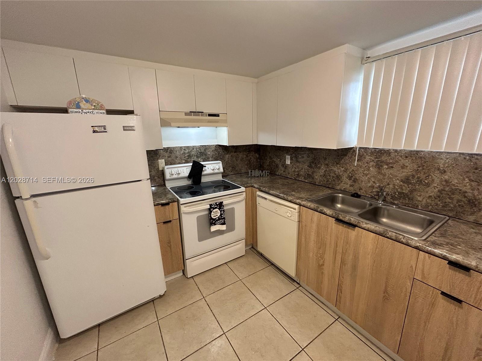 A kitchen features white upper cabinets, light wood lower cabinets, and a brown laminate countertop — 4205 N University Dr # 112, Sunrise FL 33351, SUNRISE, FL