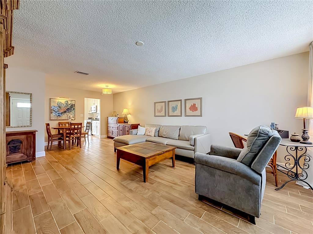 A living room with light-colored tile flooring, a sectional sofa, and an adjacent dining area — 5925 SHORE BOULEVARD S UNIT 107, GULFPORT, FL
