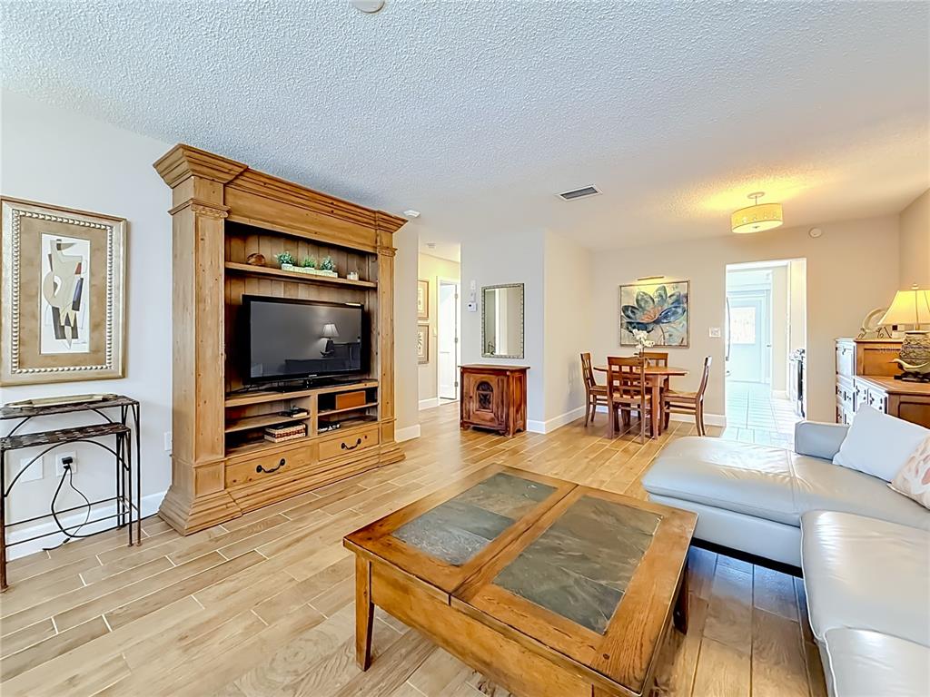 A living room features a large wooden entertainment center, a coffee table, and dining area — 5925 SHORE BOULEVARD S UNIT 107, GULFPORT, FL
