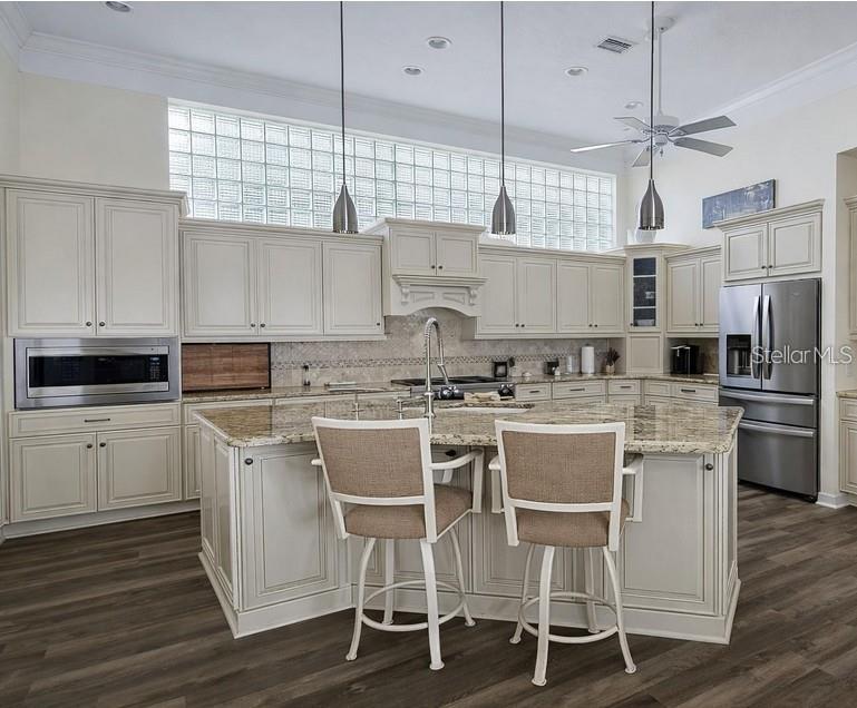 A kitchen with cream cabinets, granite countertops, a central island, and glass block windows — 618 CROSSFIELD CIRCLE, VENICE, FL