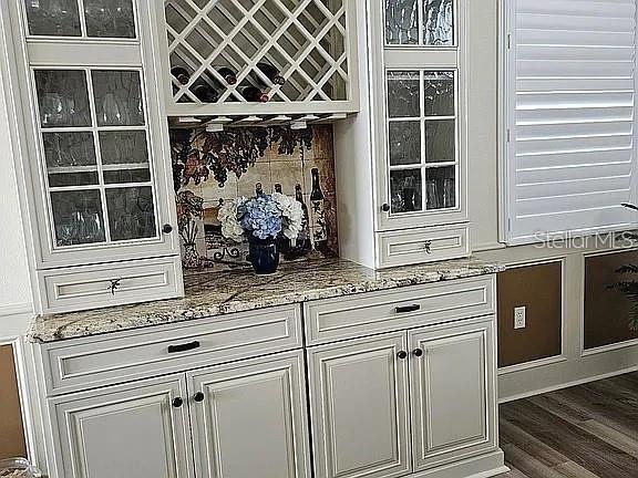 A white built-in hutch with glass cabinets, wine storage, and granite countertops in a room — 618 CROSSFIELD CIRCLE, VENICE, FL