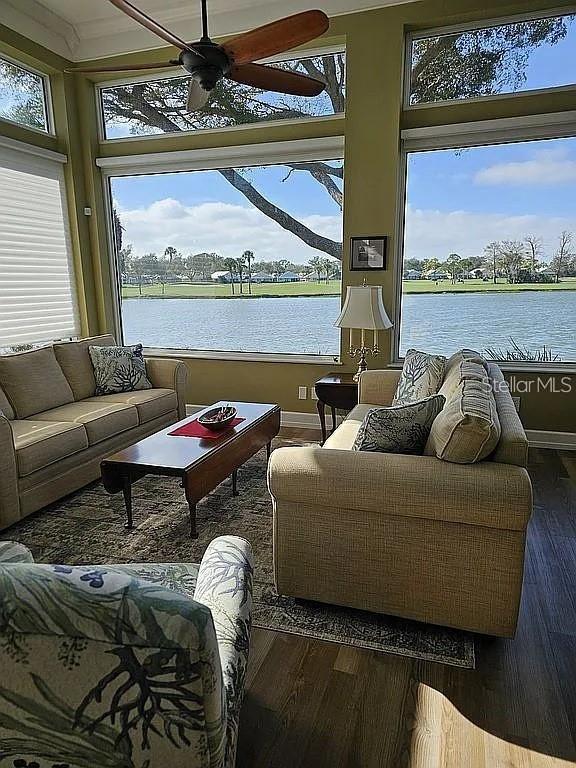 A sunroom features two sofas, a coffee table, and large windows overlooking a lake — 618 CROSSFIELD CIRCLE, VENICE, FL
