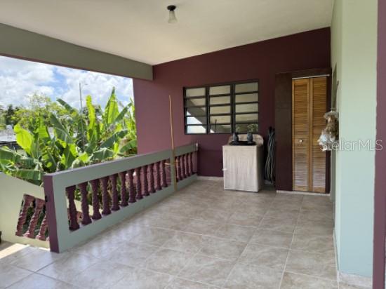 A covered outdoor balcony features tiled flooring, a decorative railing, and a laundry area — 276 ROSA SANCHEZ, YABUCOA, PR