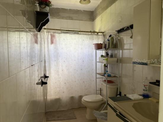 A bathroom with white tiled walls, a toilet, a shower curtain, and a vanity — 276 ROSA SANCHEZ, YABUCOA, PR