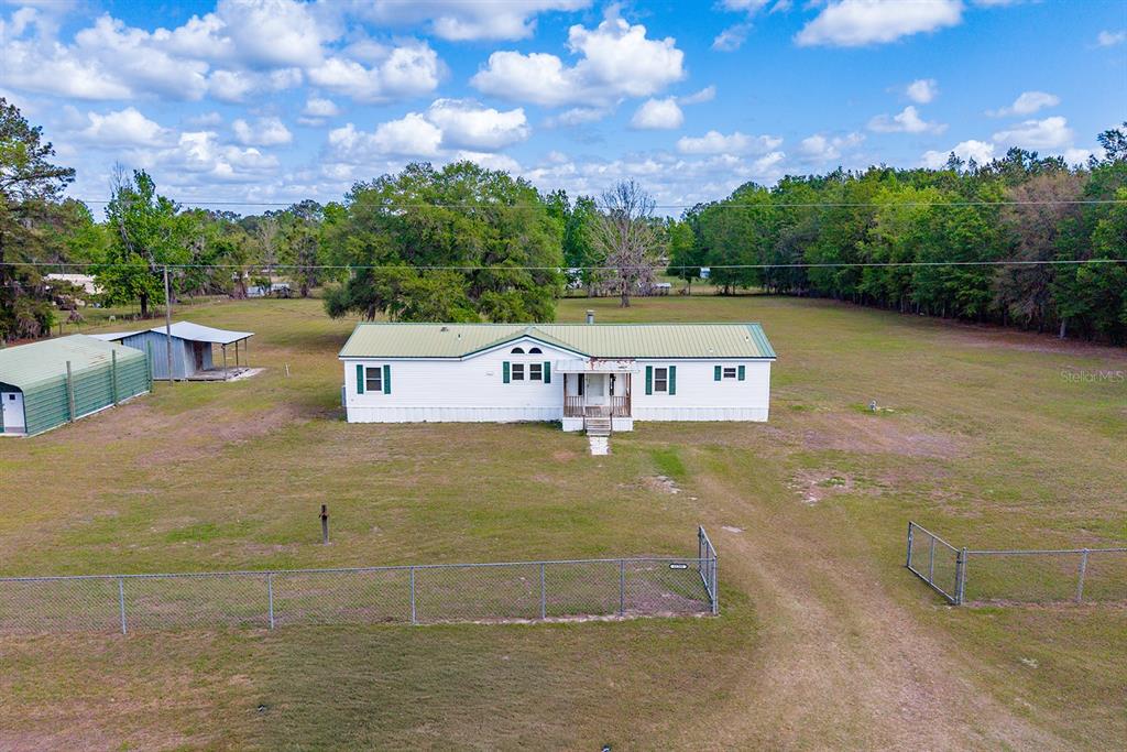 An aerial view shows a white manufactured home with a green metal roof on a lot — 11201 SW 49TH TERRACE, LAKE BUTLER, FL