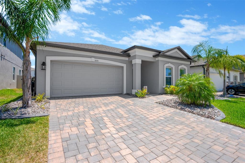 A gray single-story house features a paved driveway, a two-car garage, and palm trees — 3078 MARINE GRASS DRIVE, WIMAUMA, FL
