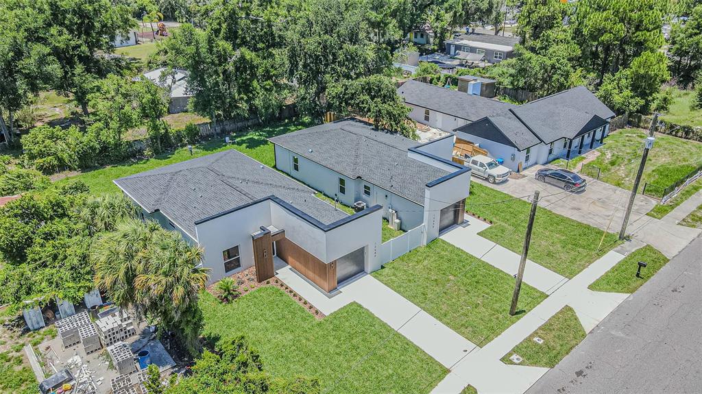 An aerial view shows two modern, flat-roofed houses with white and wood-accented exteriors and driveways — 12680 N CENTRAL AVENUE, TAMPA, FL