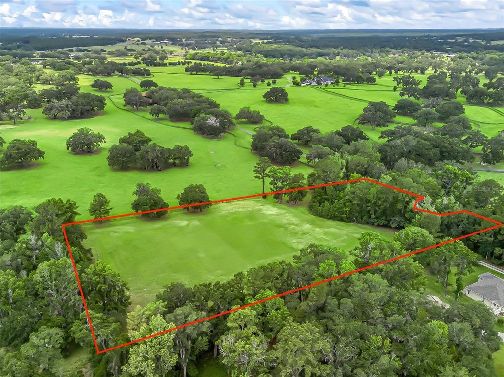 An aerial view shows a rectangular grassy lot outlined in red, surrounded by mature trees — 4698 NW 84TH TERRACE NW, OCALA, FL