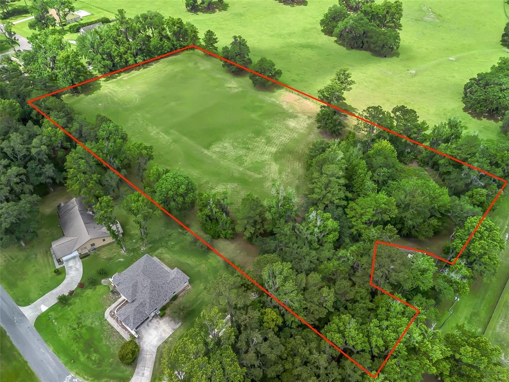 An aerial view shows a large, rectangular grassy lot outlined in red next to houses — 4698 NW 84TH TERRACE NW, OCALA, FL