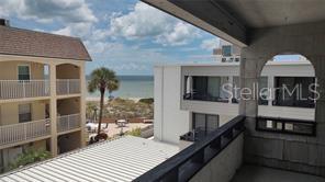A view from a balcony overlooking a beach, a palm tree, and neighboring buildings — 1555 TARPON CENTER DRIVE UNIT 262, VENICE, FL