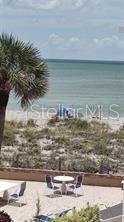 A patio with tables and chairs overlooks a sandy beach and the ocean — 1555 TARPON CENTER DRIVE UNIT 262, VENICE, FL
