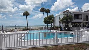 A swimming pool enclosed by a white fence sits in front of a coastal building — 1555 TARPON CENTER DRIVE UNIT 262, VENICE, FL