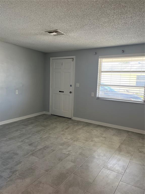 An empty room with gray walls, tiled flooring, a white door, and a window with blinds — 4945 ELKNER STREET, NEW PORT RICHEY, FL